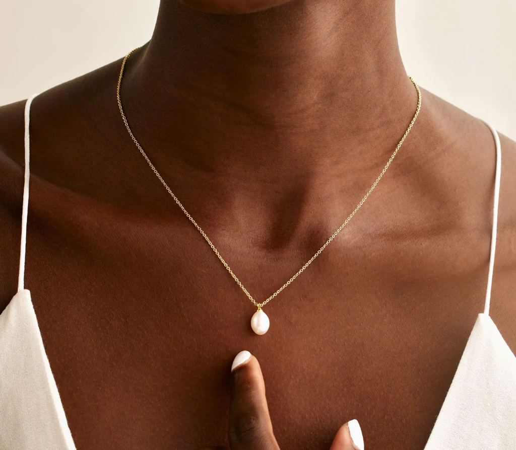 Necklace with a pendant worn by a person against a neutral background