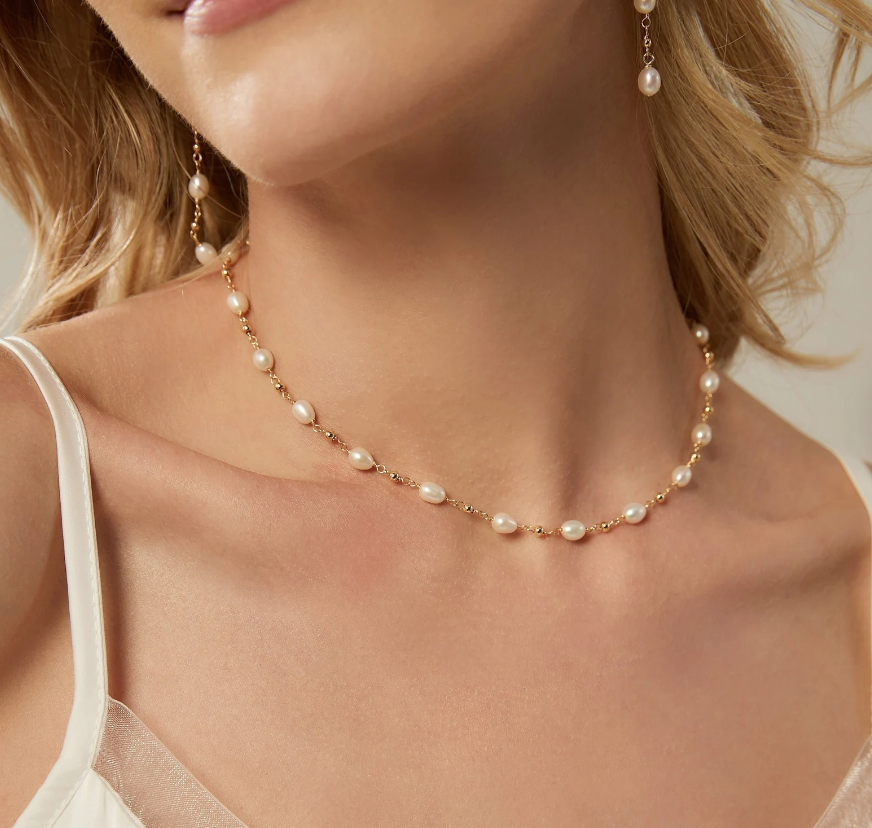 Pearl necklace and earrings on a model with a neutral background