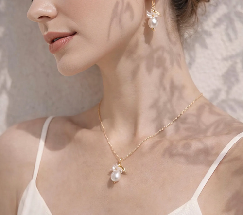 Close-up of a woman wearing a gold necklace with pearl pendant against a neutral background